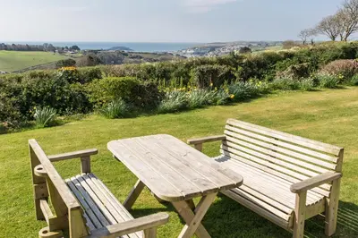a wooden picnic table and bench in a field at Bucklawren Farm in Looe