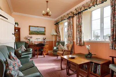a living room with a couch and chairs and a table at Bucklawren Farm in Looe