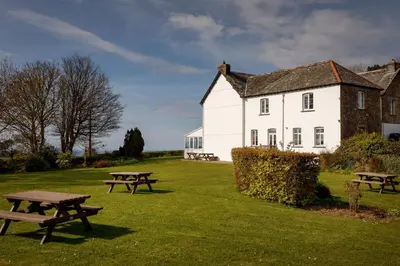 a white building with picnic tables in front of it at Bucklawren Farm in Looe