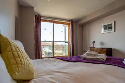 a bedroom with a large bed with a window at 2-bedroom Apartment - Fistral Beach in Newquay