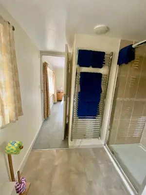 a bathroom with a walk in shower and blue towels at Lynwood House Bed and Breakfast in Tregoney