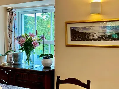 a vase of flowers on a table next to a window at Lynwood House Bed and Breakfast in Tregoney