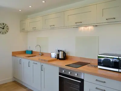 a kitchen with white cabinets and a sink and a microwave at Bosun's in Port Isaac