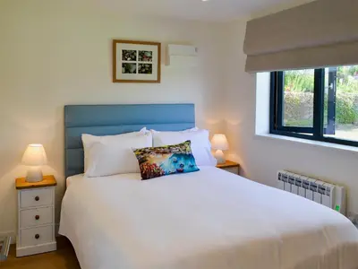 a bedroom with a white bed and two windows at Bosun's in Port Isaac