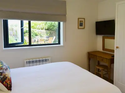 a bedroom with a bed and a window and a desk at Bosun's in Port Isaac