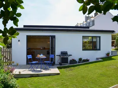 a white house with two chairs and a table in a yard at Bosun's in Port Isaac