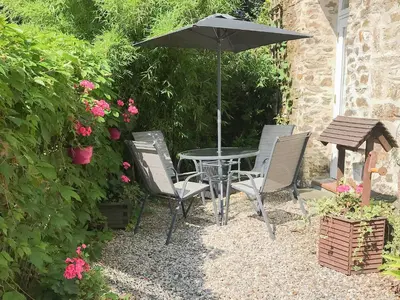 a table and chairs with an umbrella in a garden at Chapel Barn in Bodmin