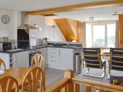 a kitchen with white cabinets and a table and chairs at Towan View Loft in Newquay