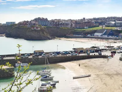 a beach with boats in the water and a city at Towan View Loft in Newquay