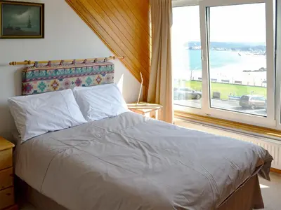 a bed in a bedroom with a large window at Towan View Loft in Newquay