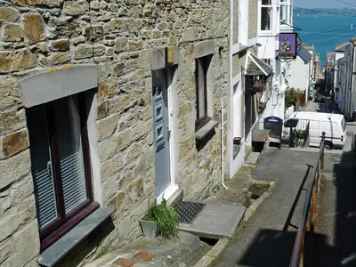 a stone building with a door on a street at Roland Cottage in Falmouth