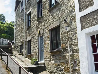 an old stone building with a blue door and stairs at Roland Cottage in Falmouth