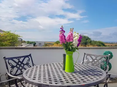 a vase with purple and white flowers on a table at Trevone in St Merryn