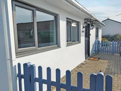 a white house with a blue fence next to it at Trevone in St Merryn