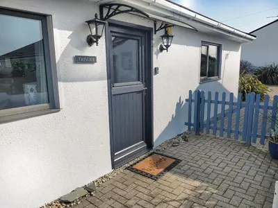 a white house with a blue fence and a door at Trevone in St Merryn