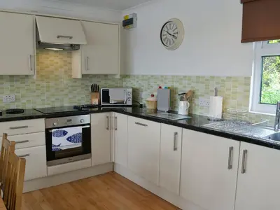 a kitchen with white cabinets and a clock on the wall at Trevone in St Merryn
