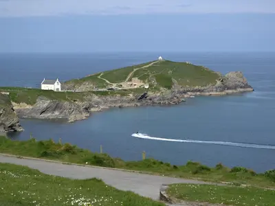 a boat in a body of water next to a house at Rosetta Apartments - Ocean Mist in Newquay