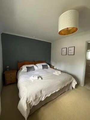 a bedroom with a large white bed with a blue wall at Bogee Farm in Padstow