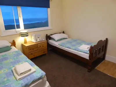 a small bedroom with two beds and a window at Longbeach- Adults Only in Newquay
