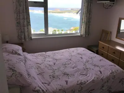 a bedroom with a bed with a view of the ocean at Surf View Apartments in Newquay