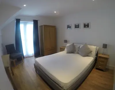 a bedroom with a bed and a chair and a window at Rawley point in Newquay