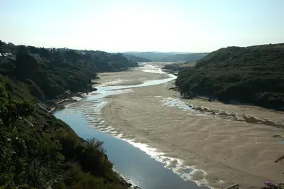 an aerial view of a river with a beach at Rawley point in Newquay