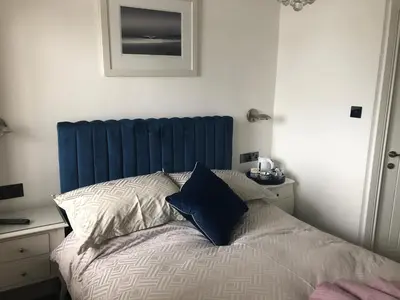 a bed with a blue headboard in a bedroom at Lazy Waves in Newquay