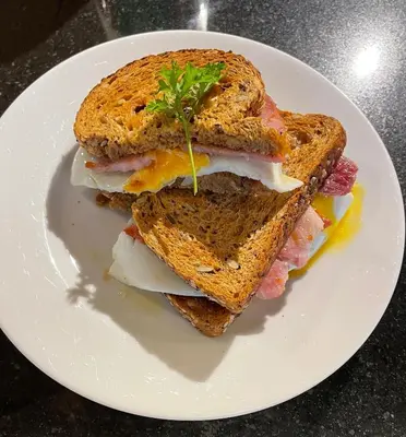 a sandwich on a white plate on a table at SPRING GARDENS B&B in Wadebridge