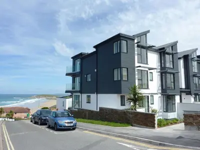 a black and white building with cars parked in a parking lot at Flat 8 Seascape in Newquay