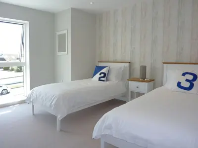 a white bedroom with two beds and a window at Flat 8 Seascape in Newquay