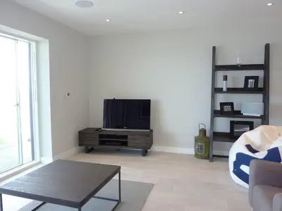 a living room with a flat screen tv on a stand at Flat 8 Seascape in Newquay