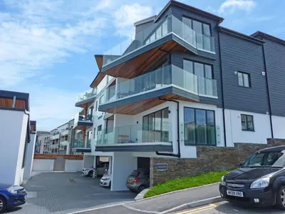 a building with glass windows and a parking lot at Flat 8 Seascape in Newquay