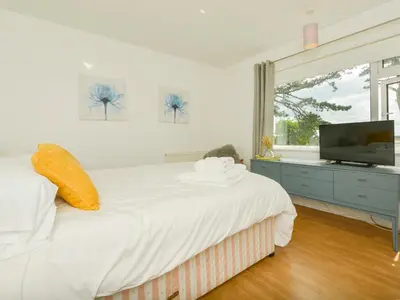 a white bedroom with a large bed and a flat screen tv at Blue Seas in Saint Mawes