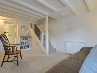 a living room with a couch and a staircase at Little Barn Cottage in Portloe