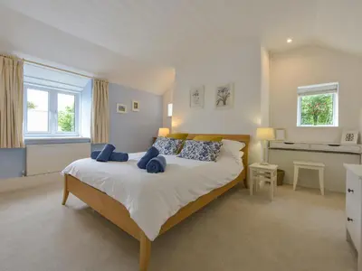 a bedroom with a large bed with blue pillows at Little Barn Cottage in Portloe