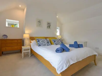 a bedroom with a large bed with blue pillows at Little Barn Cottage in Portloe
