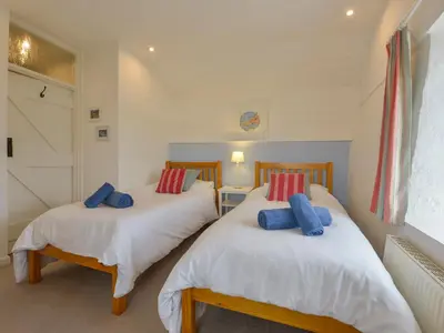 two twin beds in a room with white walls at Little Barn Cottage in Portloe