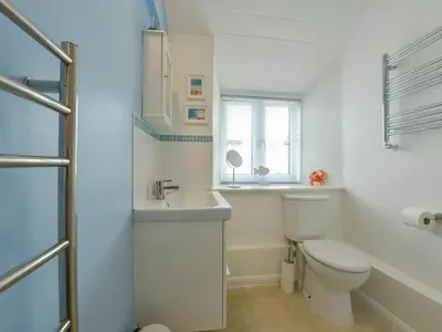 a white bathroom with a toilet and a sink at Little Barn Cottage in Portloe