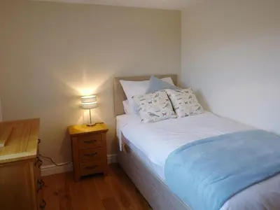 a bedroom with a bed and a night stand with a lamp at The Hayloft in Breage