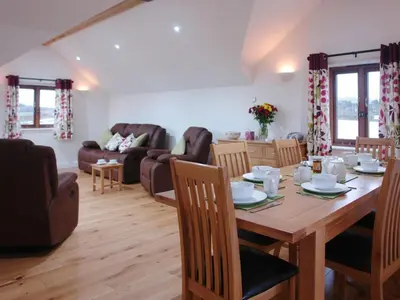 a dining room and living room with a wooden table at The Hayloft in Breage