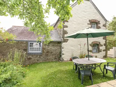 a table and chairs with an umbrella in front of a house at Badger Cottage in Mawgan