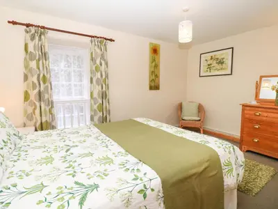 a bedroom with a bed and a window and a dresser at Badger Cottage in Mawgan