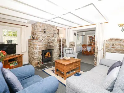 a living room with two couches and a stone fireplace at Badger Cottage in Mawgan