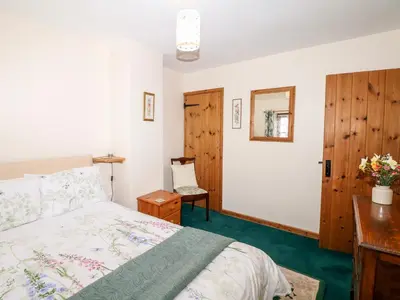 a bedroom with a bed and a desk and a mirror at Swift Cottage in Mawgan