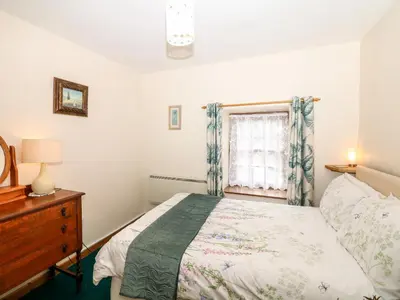 a bedroom with a bed and a window at Swift Cottage in Mawgan