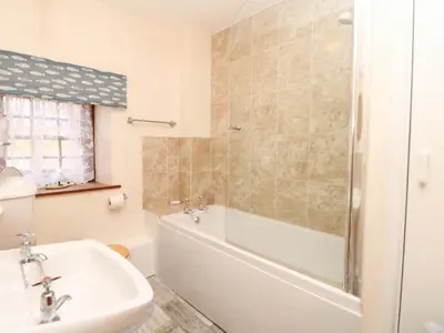 a bathroom with a bath tub and a sink at Swift Cottage in Mawgan