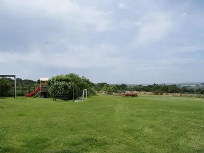 a large field with a playground with a slide at Swift Cottage in Mawgan