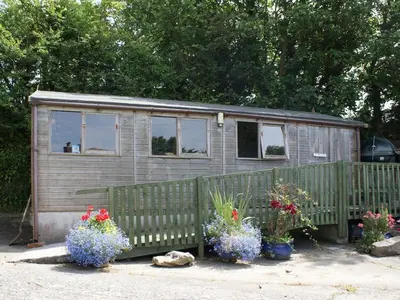 a tiny house with flowers in front of a fence at Swift Cottage in Mawgan