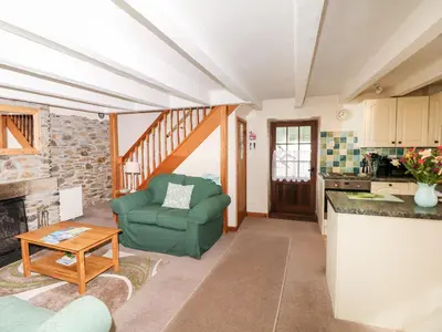 a living room with a green chair and a table at Swift Cottage in Mawgan