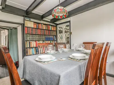 a dining room with a table with chairs and bookshelves at Boundys House in St Ives